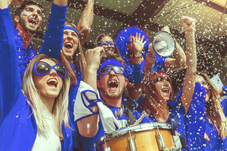 group of fans dressed in blue color watching a sports event in the stands of a stadium