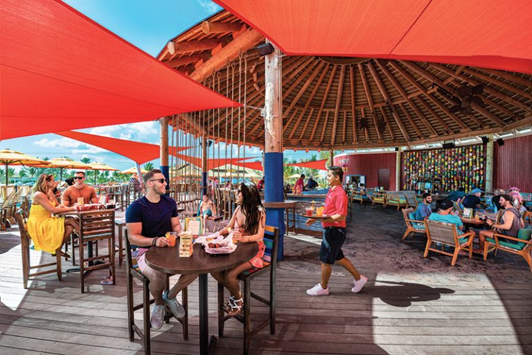 Perfect Day at Cococay, Bahamas, private island, wings, server, waiter, guests, couples, friends, relaxing at lunch with drinks at Captain Jack''s Island Grill, beach bar, restaurant, dining, fun, red umbrella decor