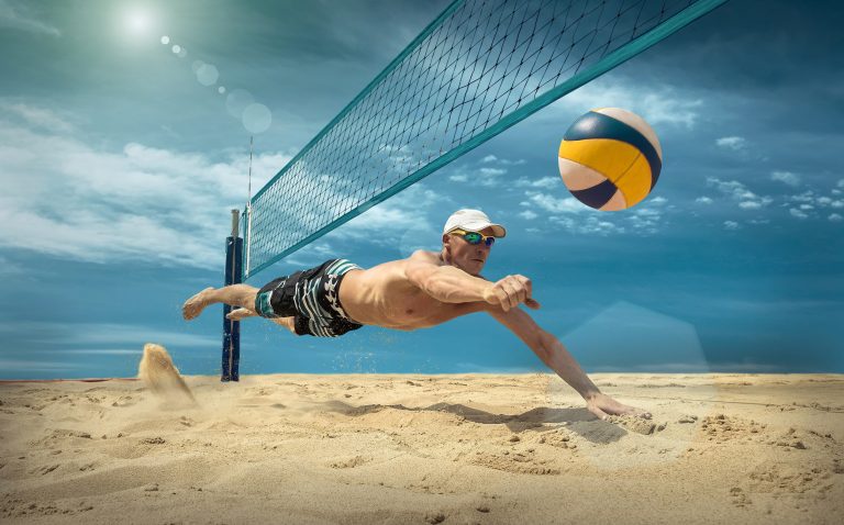 Beach volleyball player in action at sunny day under blue sky.